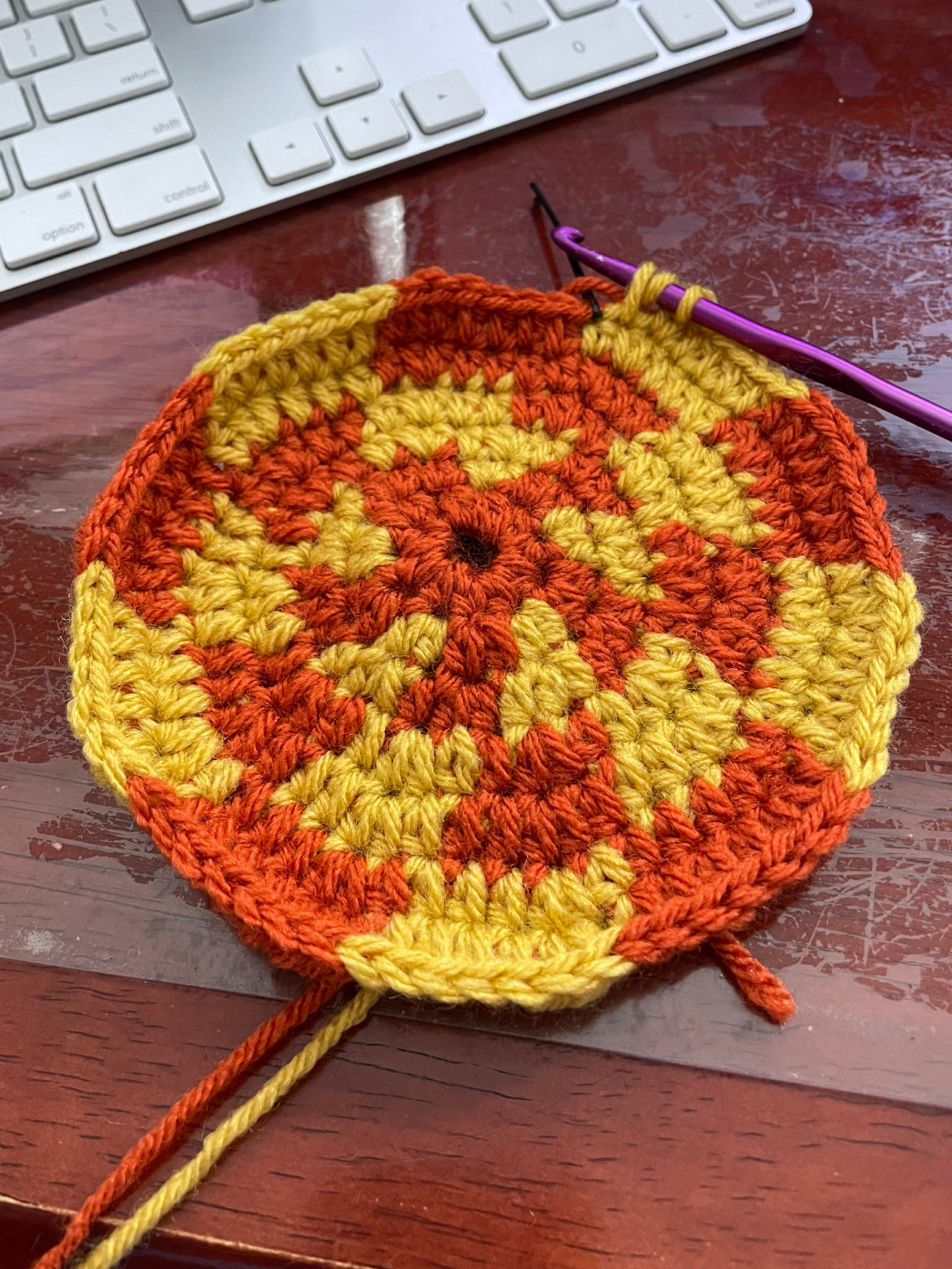 A crocheted circle with orange and yellow checkered pattern